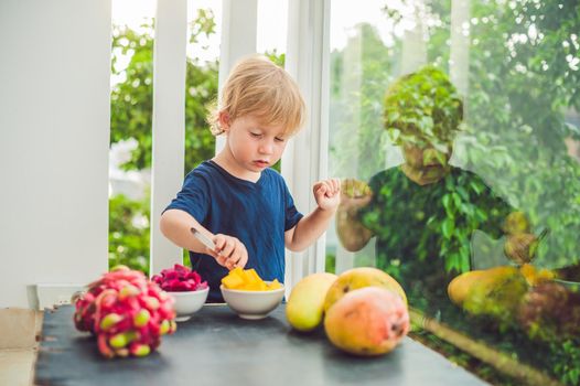 Little cute boy eating mango on the terrace.