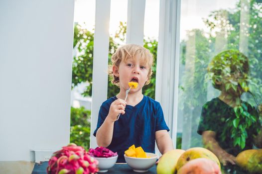 Little cute boy eating mango on the terrace.