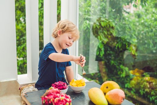 Little cute boy eating mango on the terrace.