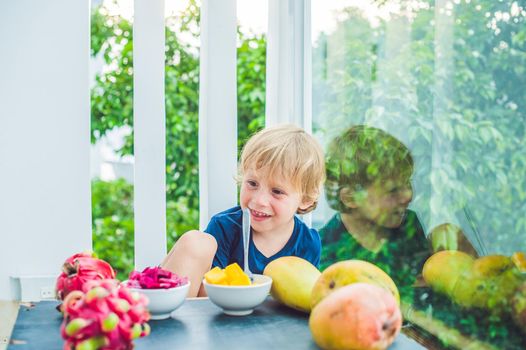 Little cute boy eating mango on the terrace.