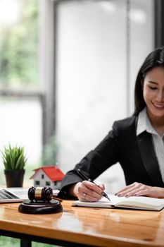 Close up business woman and lawyers discussing contract papers with brass scale on wooden desk in office. Law, legal services, advice, Justice and real estate concept