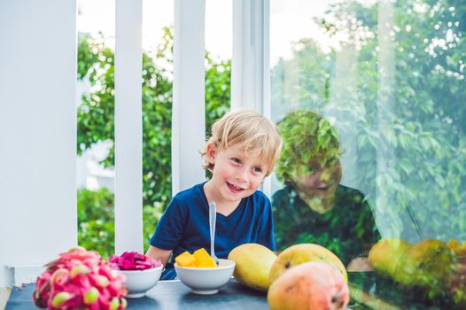 Little cute boy eating mango on the terrace.