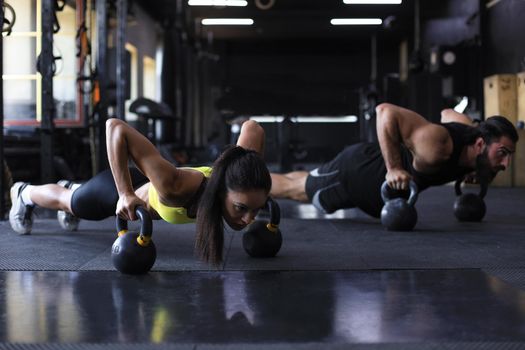 Sporty man and woman doing push-up in a gym