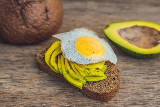 Toast with avocado and egg on rustic wooden background.