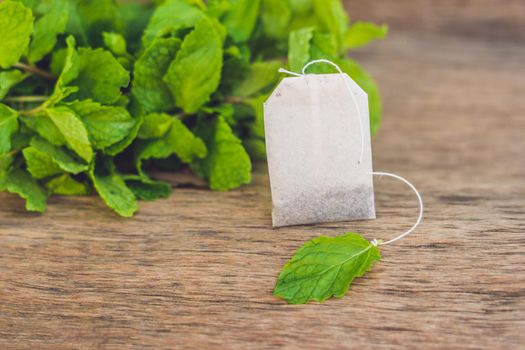 Tea bags on wooden background with fresh melissa, mint. Tea with mint concept.