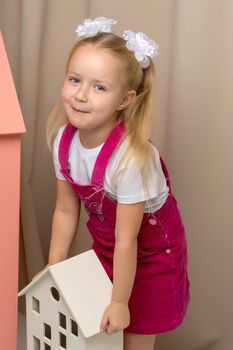 A cute little girl is playing with wooden houses. The concept of family happiness, play, creative development of the child.