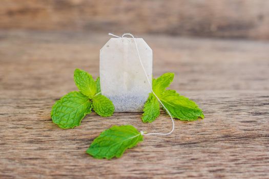 Tea bags on wooden background with fresh melissa, mint. Tea with mint concept.