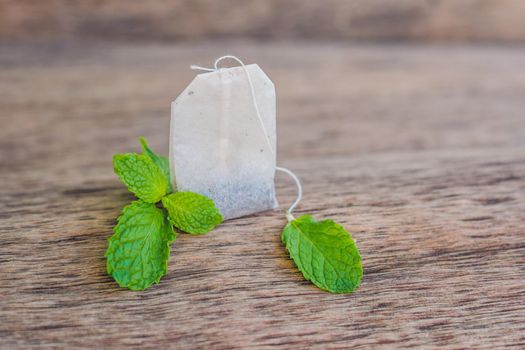 Tea bags on wooden background with fresh melissa, mint. Tea with mint concept.