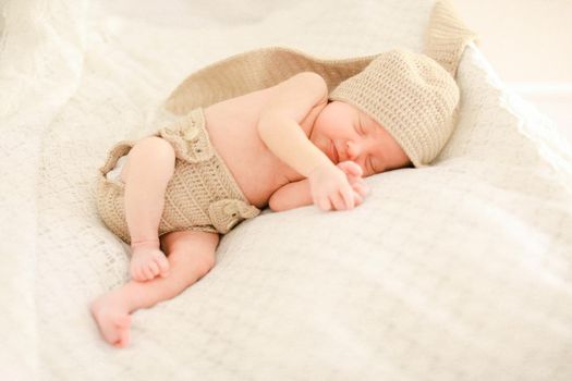 Little newborn baby sleeping and wearing crocheted clothes, white background. Concept of babies and new life.