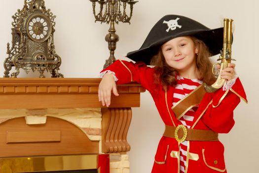 Cheerful little girl in a pirate costume and a big gun in his hand.