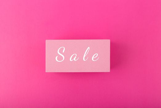 Sale elegant minimal colorful concept. Single word sale hand written on pink tablet in the middle of saturated pink background