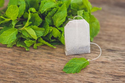 Tea bags on wooden background with fresh melissa, mint. Tea with mint concept.