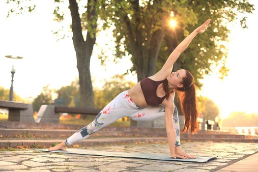 Young redhead sports woman make stretching yoga exercise outdoors