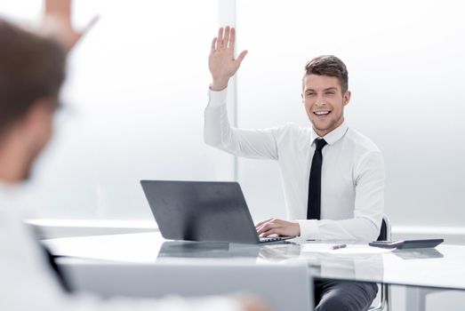 two young businessmen greet each other with a workplace in the office