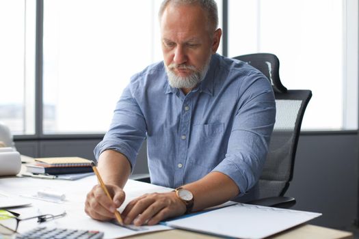 Good looking mature architect drawing something while working in the office