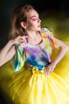 beautiful woman in long yellow dress posing dynamic in the studio