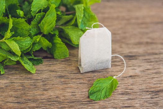 Tea bags on wooden background with fresh melissa, mint. Tea with mint concept.