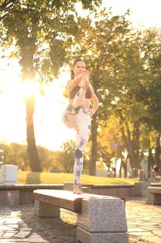 Young pretty woman doing yoga exercises in the park