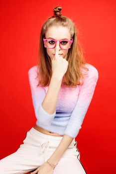 young pretty emitonal posing teenage girl on bright red background, happy smiling lifestyle people concept close up