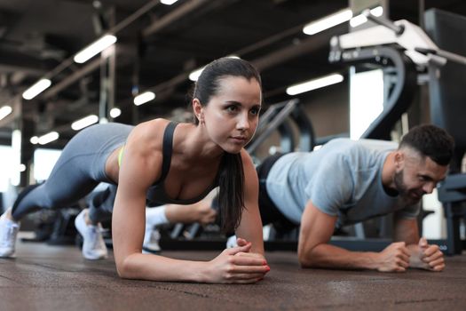 Portrait of beautiful young sports couple on a plank position