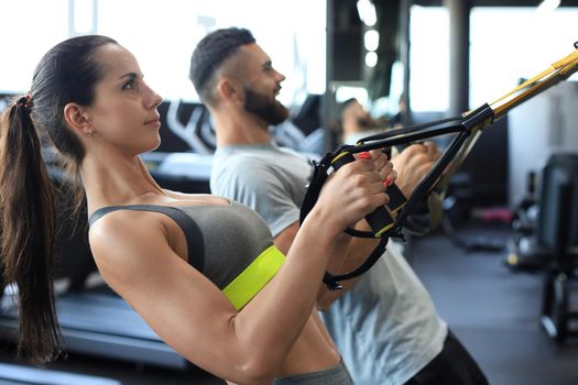 Young couple on body training with trx in gym