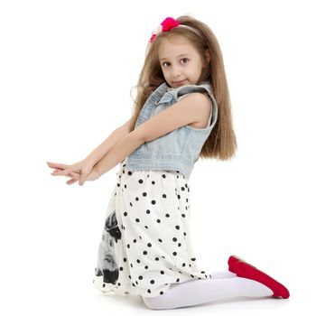 Beautiful little girl kneels in the studio on a white background. The concept of beauty and fashion, children's emotions. Isolated.