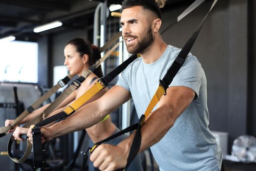 Young couple on body training with trx in gym