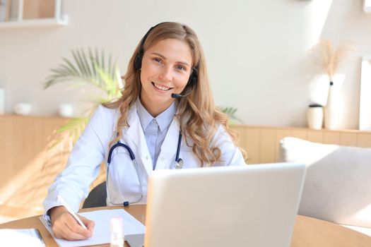 Concentrated doctor working online with a laptop sitting in a desk in a consultation