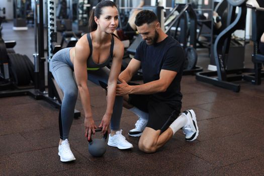 Fitness instructor exercising with his client at the gym