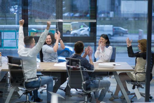 Group of young business people looking happy while celebrating success at their working places in startup office