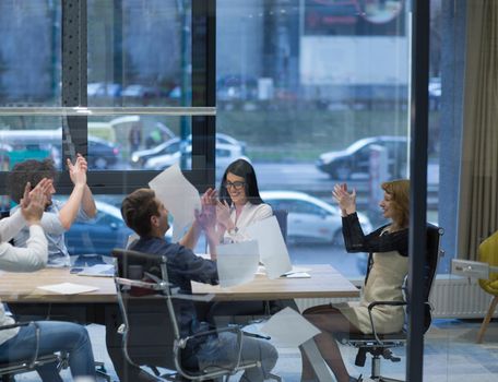 Group of young business people throwing documents and looking happy while celebrating success at their working places in startup office