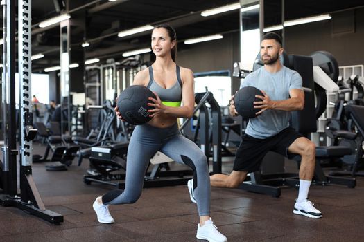 Attractive couple doing fitness with medcine ball at gym