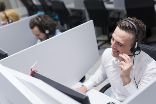 young smiling male call centre operator doing his job with a headset