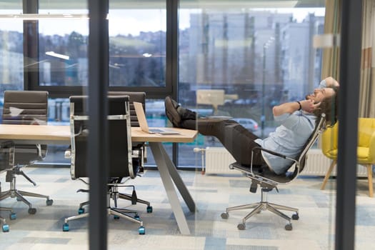 A time for relax. Young tired casual businessman relaxing at the desk in his office