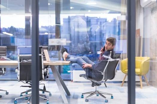 A time for relax. Young tired casual businessman relaxing at the desk in his office