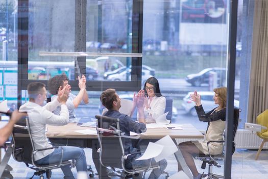 Group of young business people throwing documents and looking happy while celebrating success at their working places in startup office