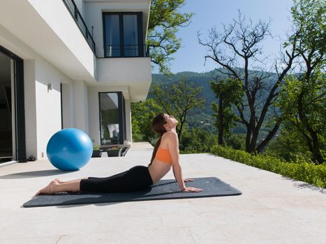 young handsome woman doing morning yoga exercises in front of her luxury home villa