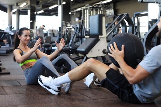 Fit and muscular couple exercising with medicine ball at gym