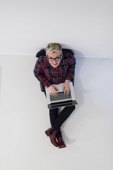 top view of young business woman working on laptop computer in modern bright startup office interior, sitting on floor