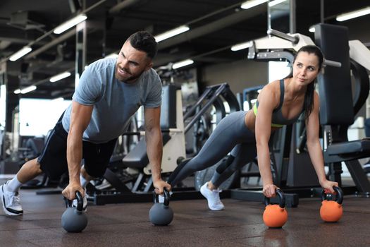 Sporty man and woman doing push-up in a gym
