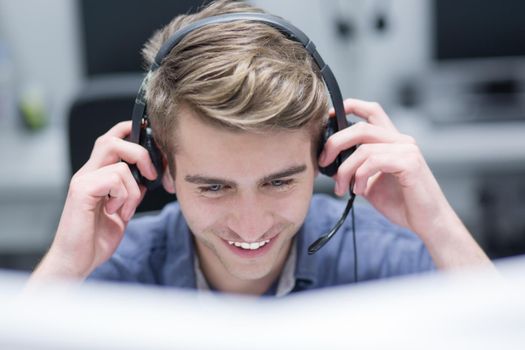 young smiling male call centre operator doing his job with a headset