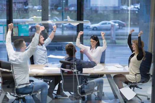 Group of young business people throwing documents and looking happy while celebrating success at their working places in startup office