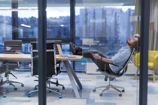 A time for relax. Young tired casual businessman relaxing at the desk in his office