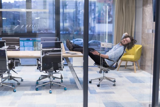 A time for relax. Young tired casual businessman relaxing at the desk in his office