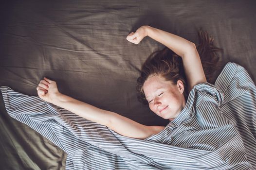 Beautiful young woman lying down in bed and sleeping, top view. Do not get enough sleep concept.