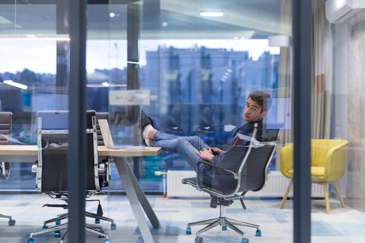 A time for relax. Young tired casual businessman relaxing at the desk in his office