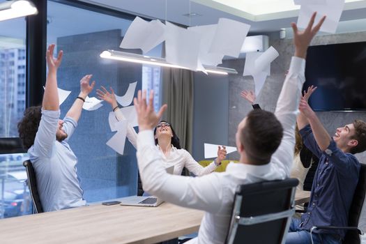 Group of young business people throwing documents and looking happy while celebrating success at their working places in startup office