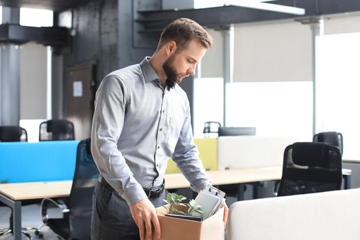 Sad dismissed worker are taking his office supplies with him from office