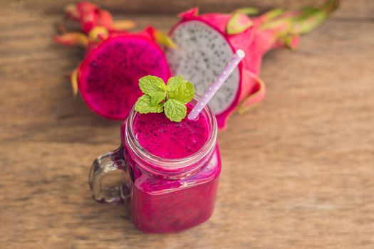 Smoothies of a red organic dragon fruit on an old wooden background.