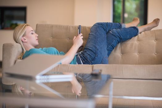 young happy woman on sofa using tablet computer at luxury home